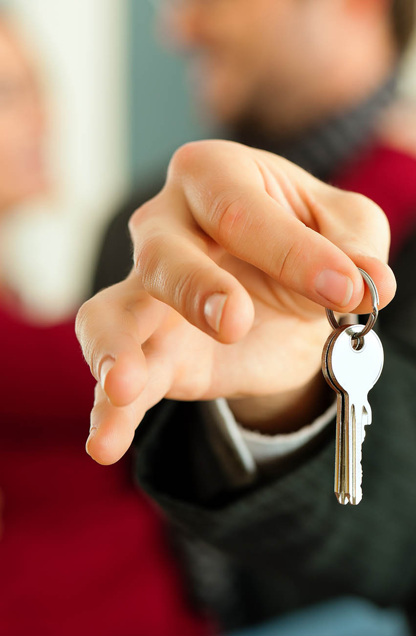 Real estate agent handing the keys to a new house to a couple after home inspection services